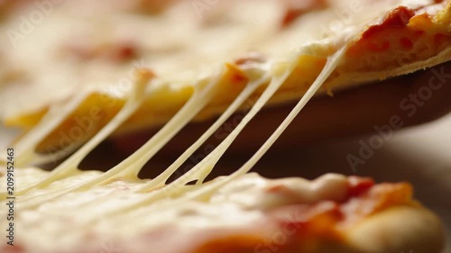 Cheese pizza slice being lifted from the pie, showcasing melted cheese stretching and pulling away from the crust, with a warm, inviting background
