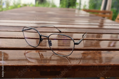 Canvastavla Glasses lying on a garden table after rain, wet surface, weather outside, autumn