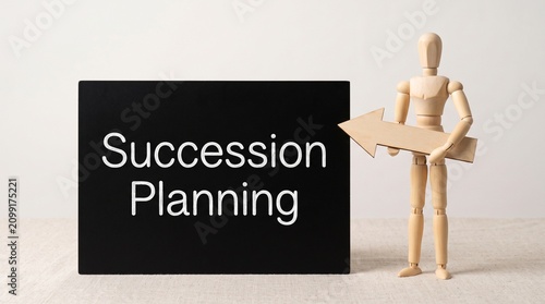 Succession planning business concept, wooden mannequin holding arrow pointing to succession planning text, corporate leadership transition strategy