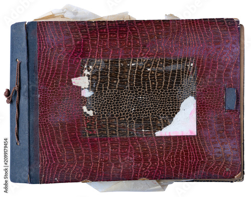Vintage worn photo album with torn red leather cover and old papers on white