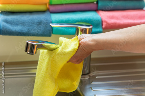 Quadro su tela Hand Cleaning Chrome Kitchen Faucet with Yellow Microfiber Cloth and Colorful Cl