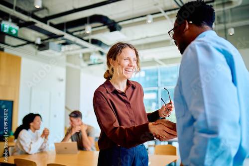 Foto Business partners forming an agreement and connection shaking hands, smiling in