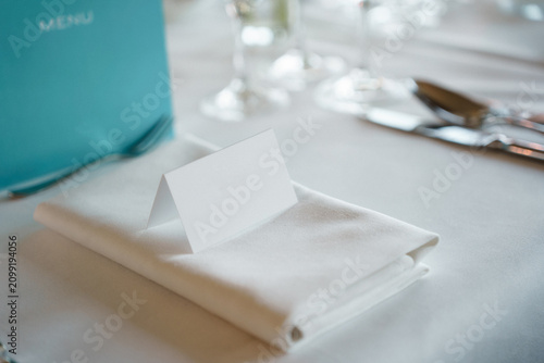 Quadro su tela Blank white folded place card on a neatly folded napkin, table setting for a wed
