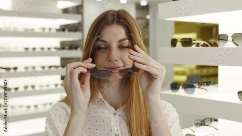 Beautiful woman examines glasses in retail store