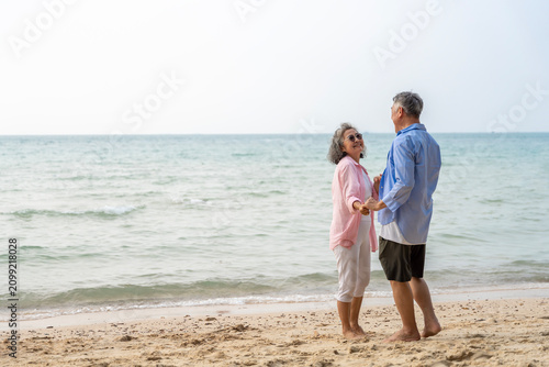 Happy Senior Asian Couple Dancing Joyfully on the Beach, Retirement Travel Lifestyle