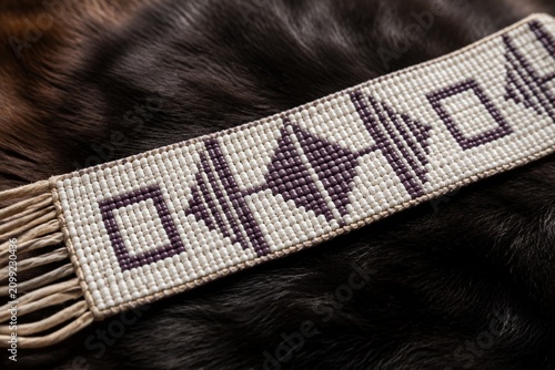Traditional belt woven with white and purple wampum beads on fur.