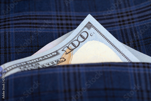 Canvastavla A crisp one hundred dollar bill partially visible in the pocket of a blue plaid fabric, symbolizing wealth, savings, and finance