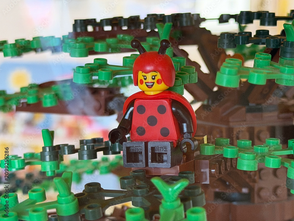 Obraz premium Toy ladybug figure sitting in a lego style tree with green leaves, playful kids building scene.