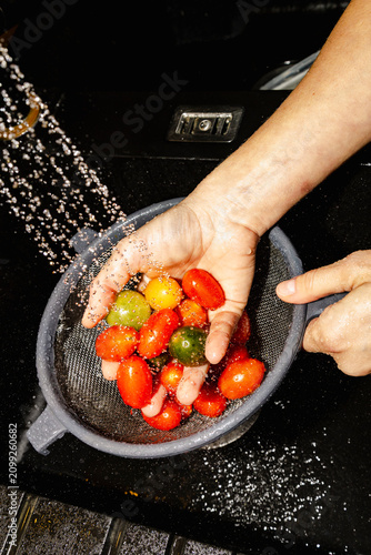 Hands rinsing colorful tomatoes for fresh healthy dinner prep