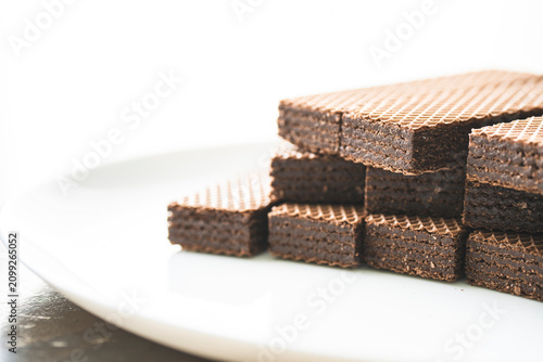 Crispy wafer sticks with chocolate filling on a white porcelain plate
