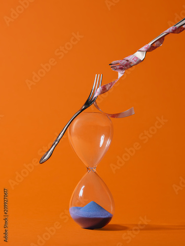 Balancing act of forks and measuring tape on hourglass symbolizes