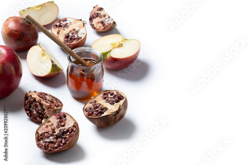 Traditional Rosh Hashanah food with apples, honey and pomegranates on white background