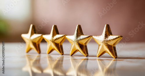 Gold stars lined up on a table with blurred background showing warm light and soft colors