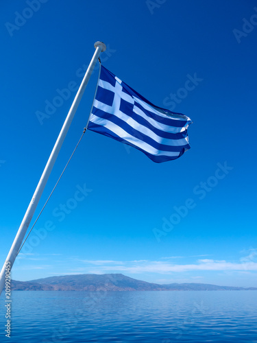 Fotografie A Greek flag fluttering in the wind on a ferry in the Aegean Sea in Greece