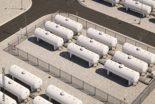 Tableau sur toile Industrial storage tanks lined up in a secure facility with fencing and piping