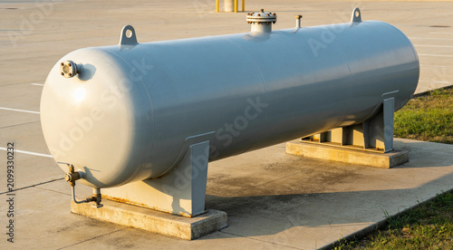 Large industrial propane tank resting on concrete supports outdoors