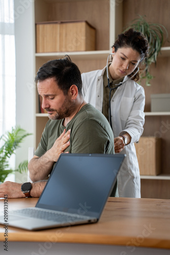 A female doctor at the clinic performs auscultation of the lungs of a patient with symptoms of pneumonia.