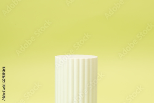 Minimalist white fluted cylinder podium on soft green background for product presentation