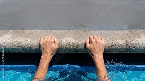 Swimmer Hands Gripping Starting Block with Blue Ripple Water