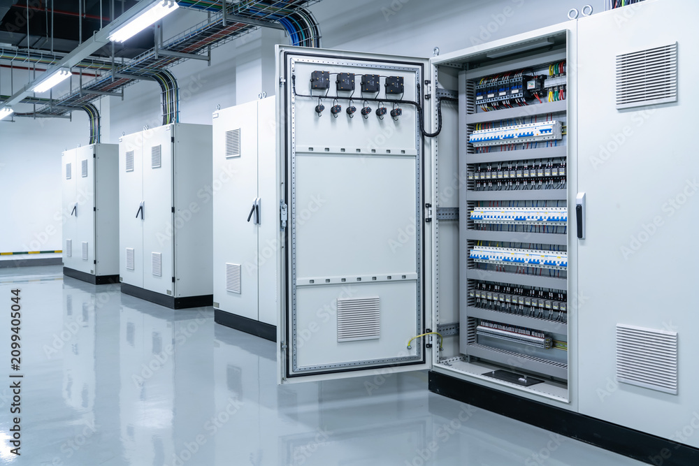 Fototapeta premium Modern electrical control panel room with rows of distribution cabinets and wiring