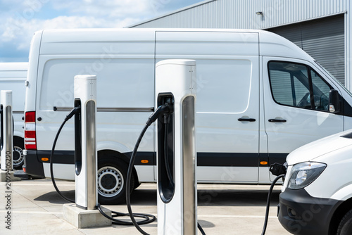 Obraz na płótnie Electric vans charging at a modern charging station in an outdoor lot