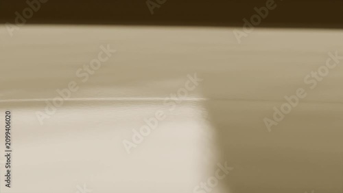 Droplet hitting tan surface creating bouncing drops and ripples at tray, shifting bright rectangle