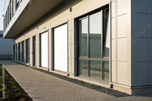 Modern commercial building facade with glass windows and blank white panels
