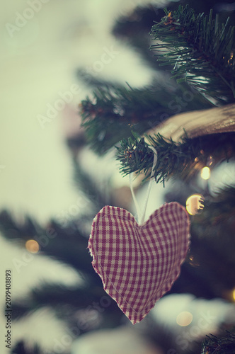 Close-up of a Heart shape ornament hanging on an illuminated Christmas tree