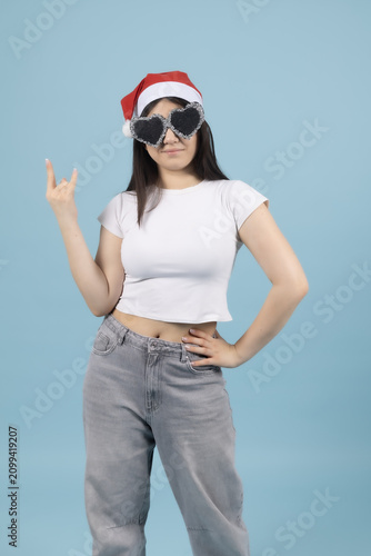 Happy young woman in red santa hat pointing fingers to the side wall