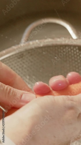 Vertical video: Rinsing carrot with hands as tap runs at kitchen sink to clean, colander, wristband