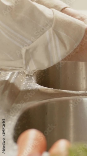 Vertical video: Seeing drops, wrist rolling cuff to keep sleeve dry, wiping kitchen sink rim, watch