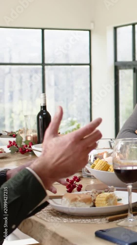 Vertical video: Talking left diner in green top gesturing grabbing fork reaching glass at home meal