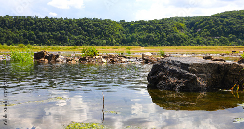 Picturesque stone rapids on the shallow water of a clean river. Picturesque landscape, wild nature in summer. Dniester in Ukraine.