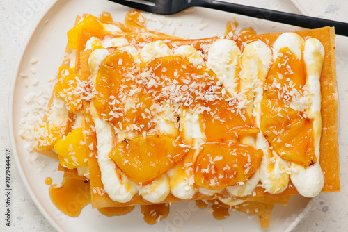 Obraz na plátně Mille-feuille with caramelized pineapple, mango, whipped cream and coconut