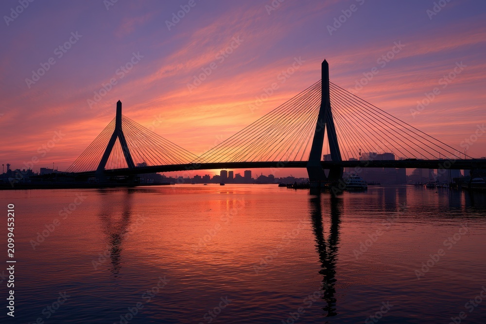Obraz premium Sunset over a modern cable-stayed bridge on a Massachusetts waterfront