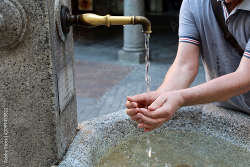 Konstfotografi Close up of hands drinking fresh water from a public fountain.