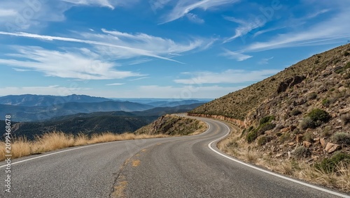 Winding Road Through Hills With Distant Mountains on a Sunny Day