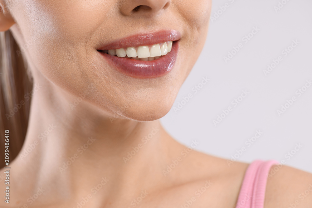 Obraz premium Happy woman with healthy teeth on light background, closeup