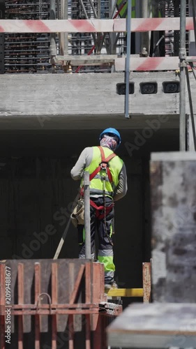 Workers build a structure with safety measures in place at a construction site during the daytime