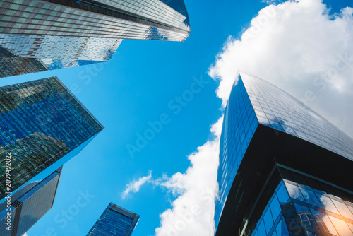 Canvas Print Tall glass skyscrapers of business offices in city reflect blue sky, clouds, and other skyscrapers