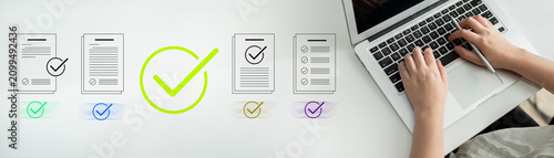 Fotografie A woman types on a laptop surrounded by checklists and papers, symbolizing achievement and productivity in a professional workspace focused on task completion