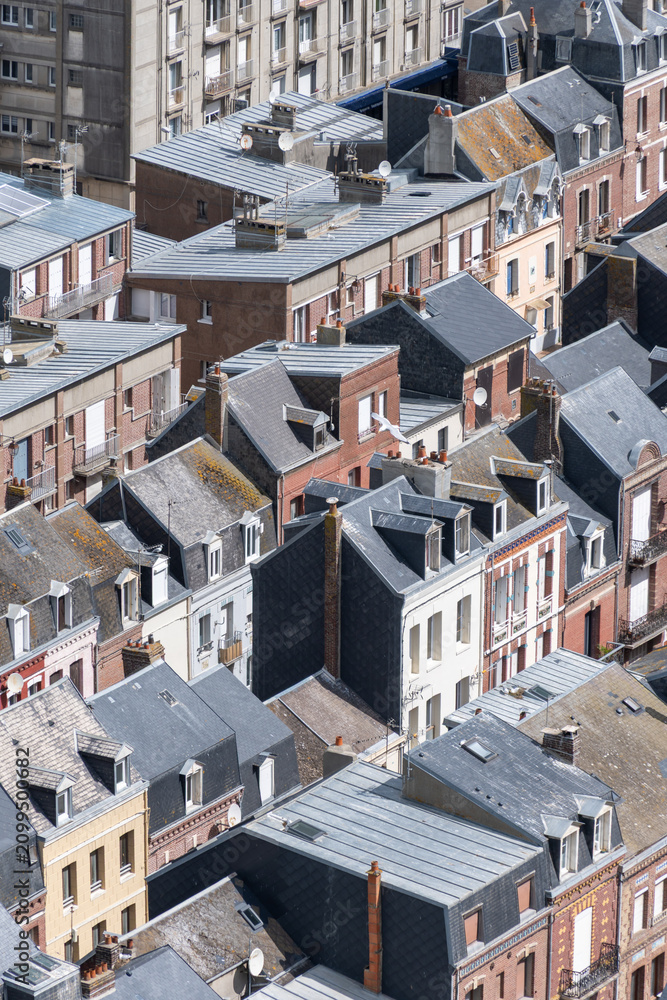 Fototapeta premium Views of Le Treport, seaside resort in Normandy, France, with white cliffs along English Channel, fishing industry and old buildings, travel destination in France, houses roofs background