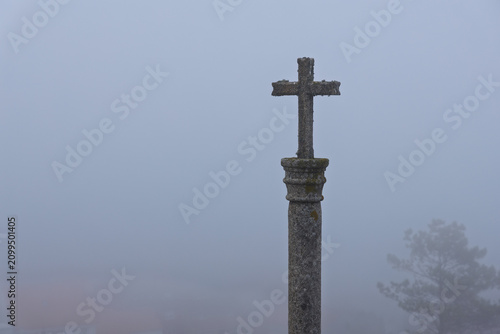 Obraz na plátne Stone christian cross standing in dense fog