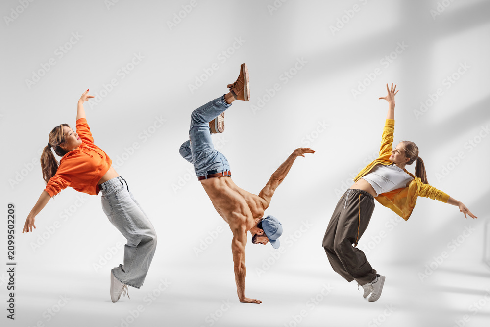 Obraz premium Guy performing handstand and two girls dancing