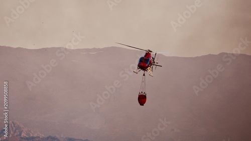 Aerial Firefighting Helicopter with Water Bucket in Smoky Sky