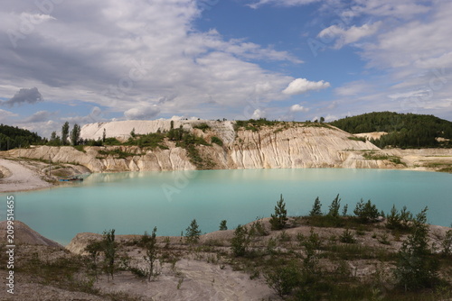 Turquoise lake in a kaolin quarry under dramatic clouds