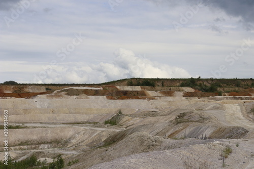 Layered kaolin quarry landscape with dramatic cloudy sky