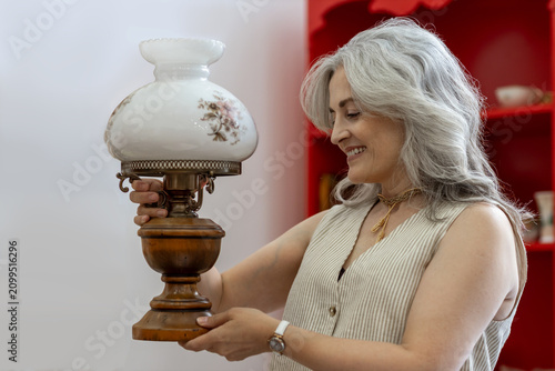 Mature woman smiling holding antique oil lamp