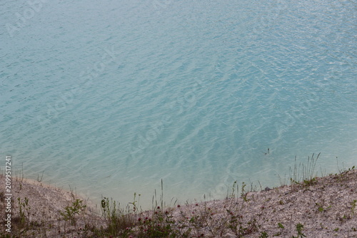 Turquoise quarry lake with white sandy shore