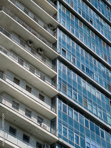High blue apartment tower with clean facade surfaces and large residential glass windows